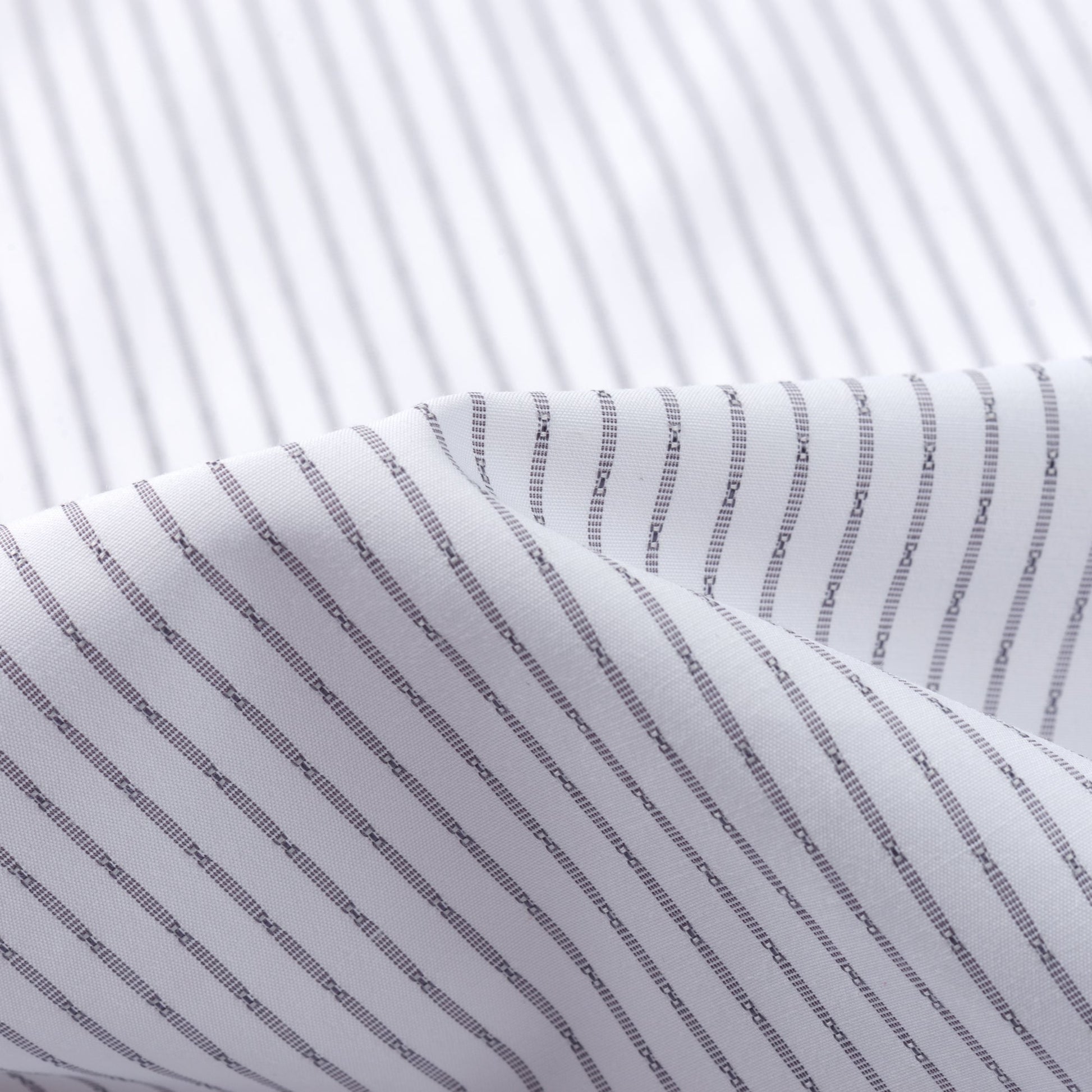 A close-up of white fabric with thin black vertical stripes and gentle folds—perfect for the FAHIZO Mens Dress Shirt Regular Fit Casual Long Sleeve Stripe Stretch Solid, combining style and comfort.